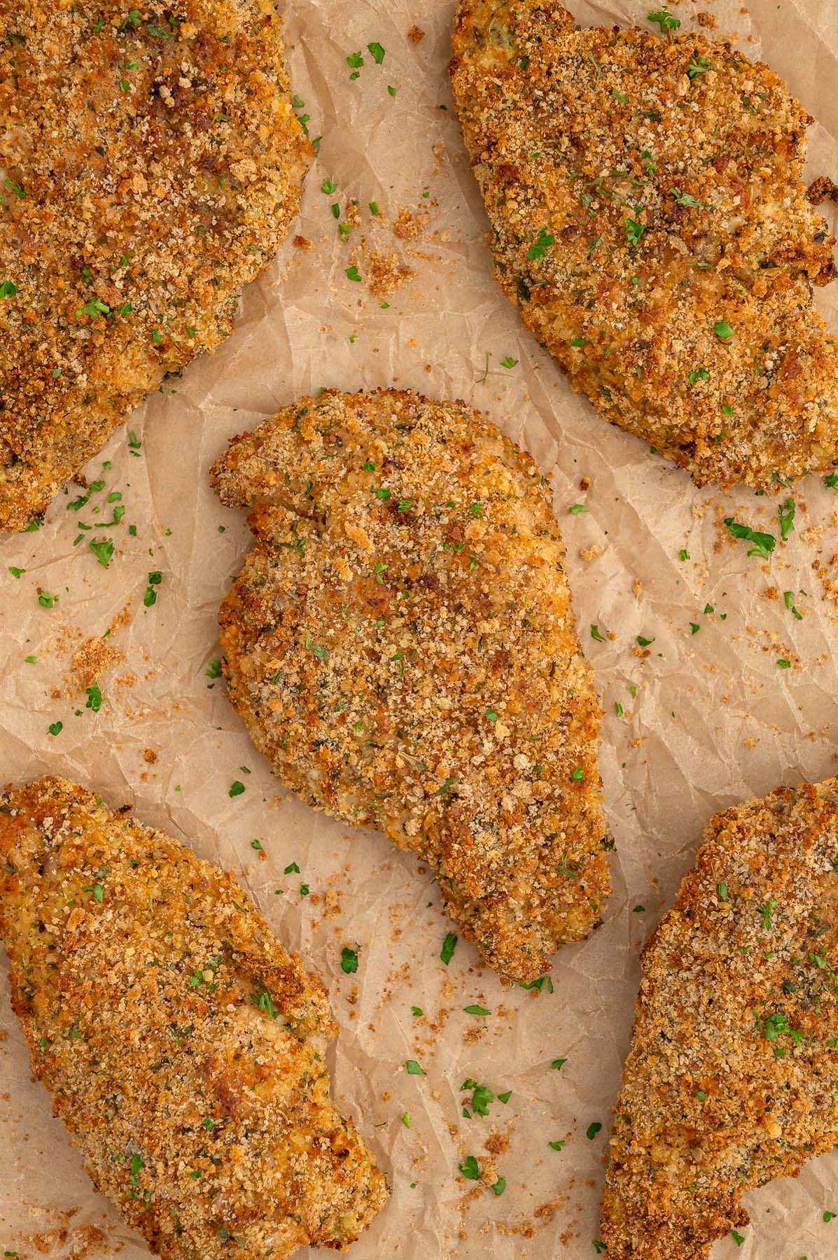 Baked chicken cutlets on a piece of parchment paper.