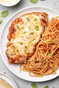 A plate of baked chicken parmesan with pasta