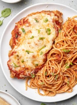 A plate of baked chicken parmesan with pasta