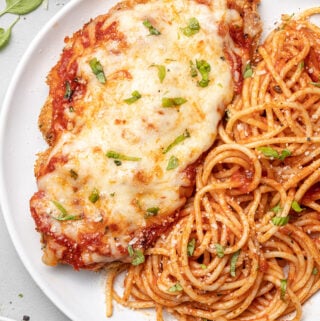 A plate of baked chicken parmesan with pasta