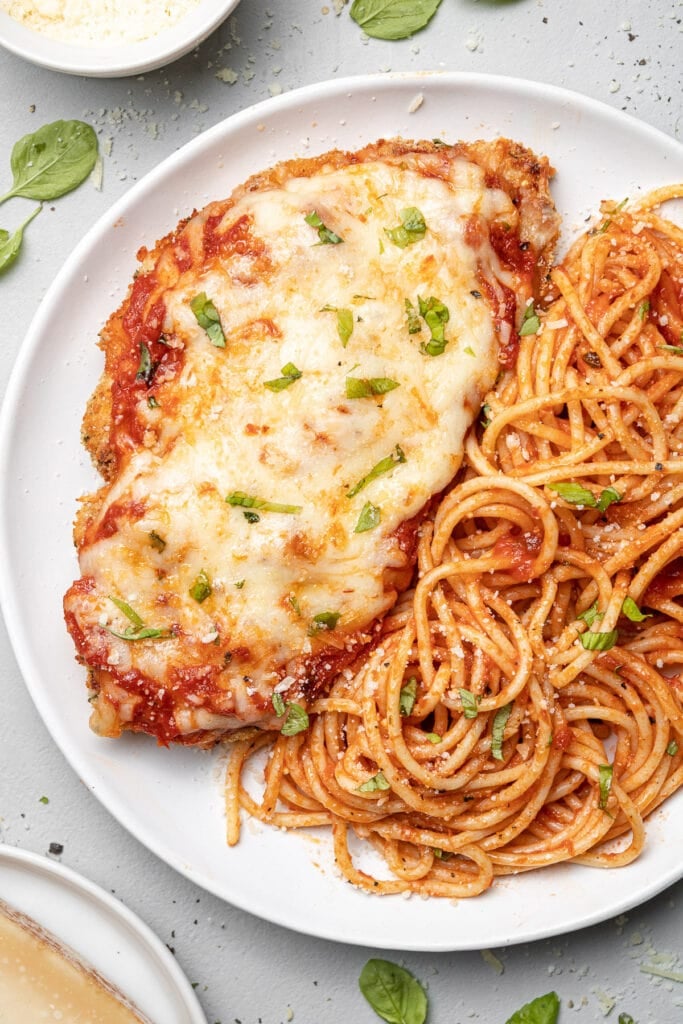 A plate of baked chicken parmesan with pasta
