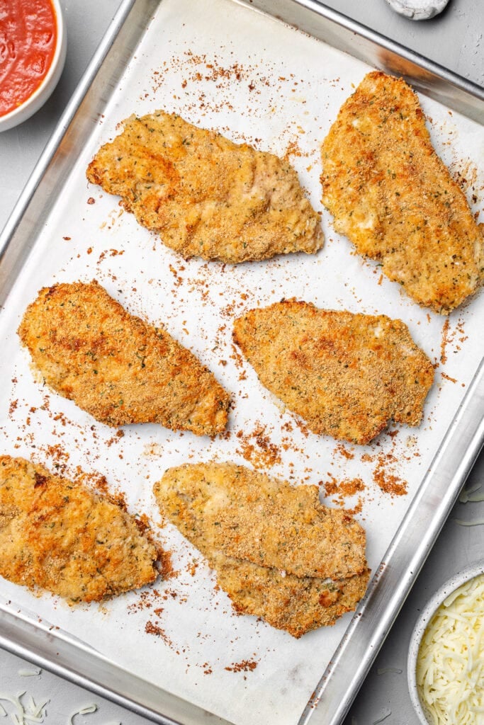 Breaded chicken cutlets cooked on a sheet pan for easy chicken parmesan