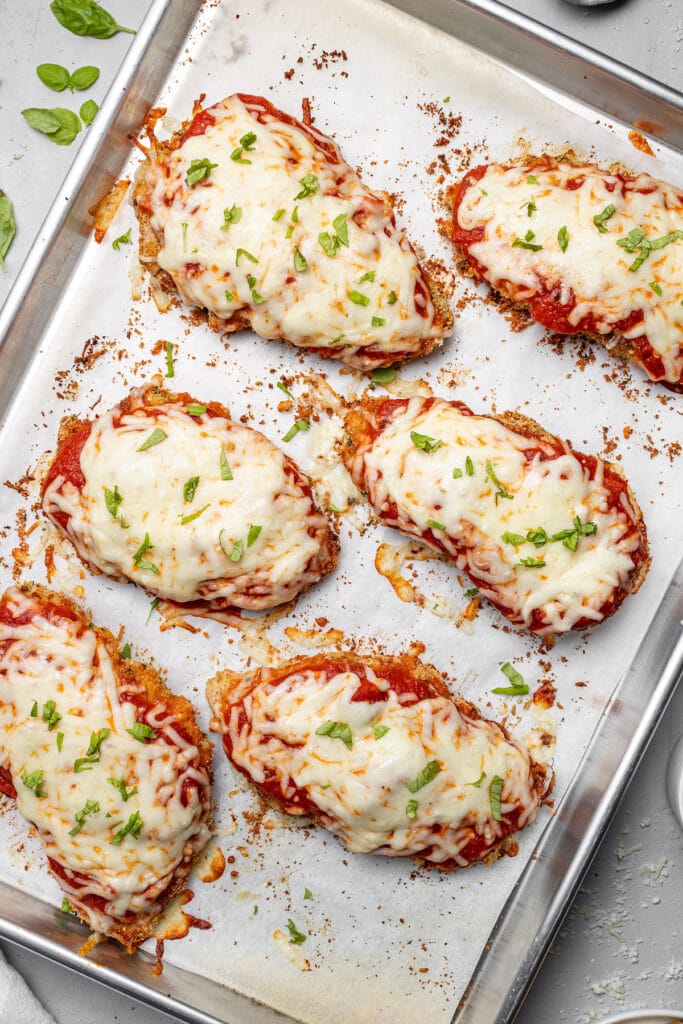 Breaded chicken cutlets cooked on a sheet pan for easy chicken parmesan with marinara sauce and melted cheese on top