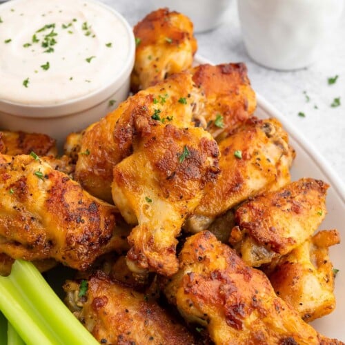 Baked Chicken Wings on a plate with celery and a container of ranch dip on the side.