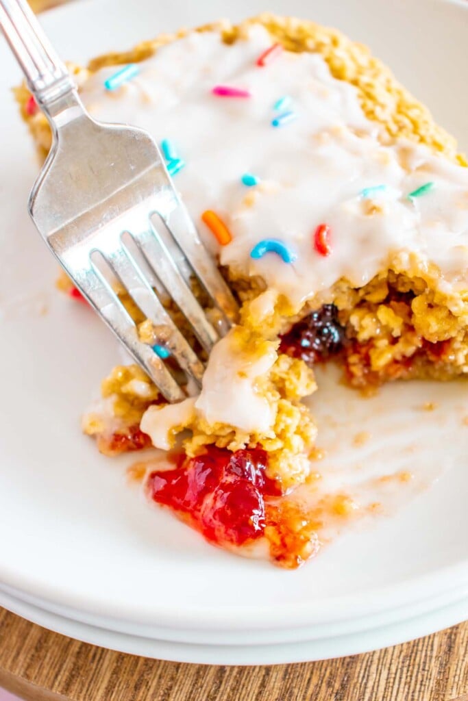 A fork taking a bite out of a piece of baked oats on a white plate