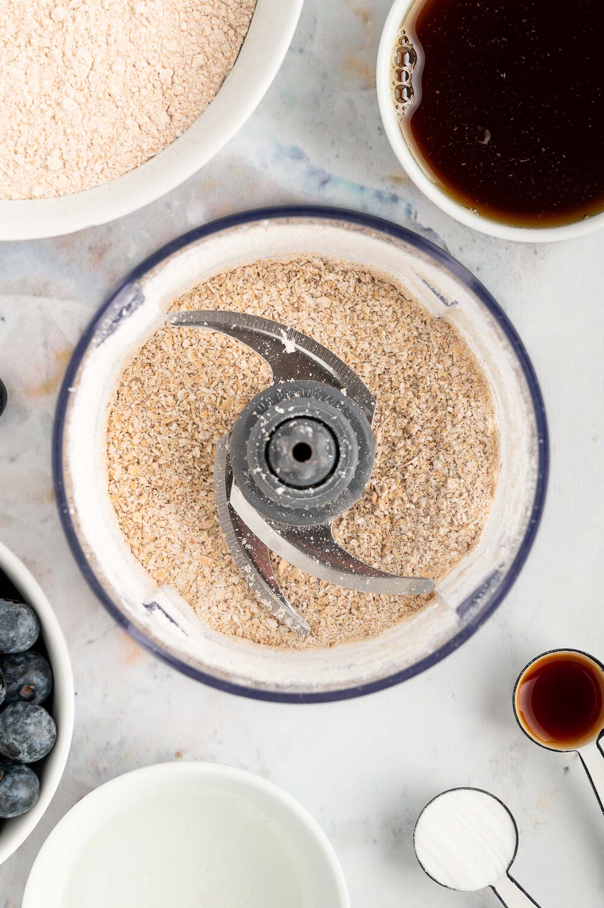 An overhead shot of oats after blending in a food processor to make oat flour for banana blueberry muffins