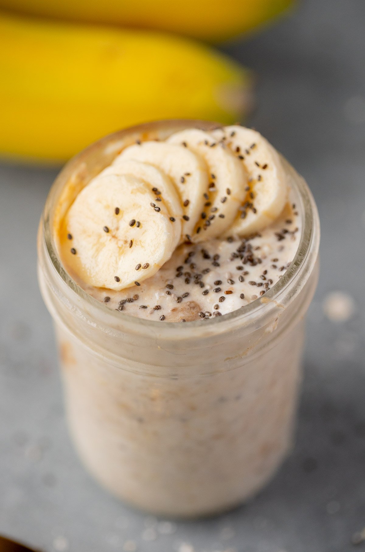 A mason jar with banana overnight oats with sliced bananas and chia seeds on top