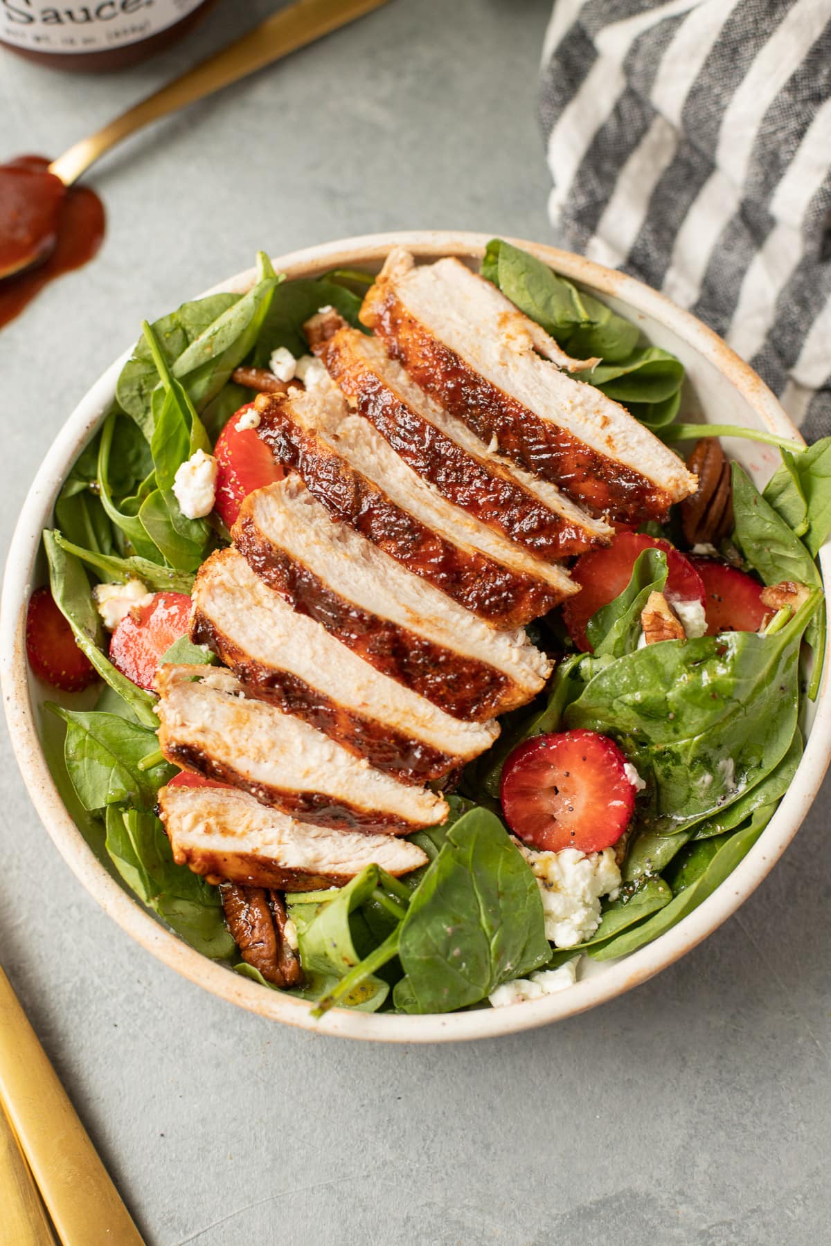 A close up of BBQ Chicken breasts sliced on top of a salad