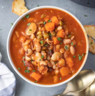 a bowl of 15 bean soup with spoons on the side on a grey background
