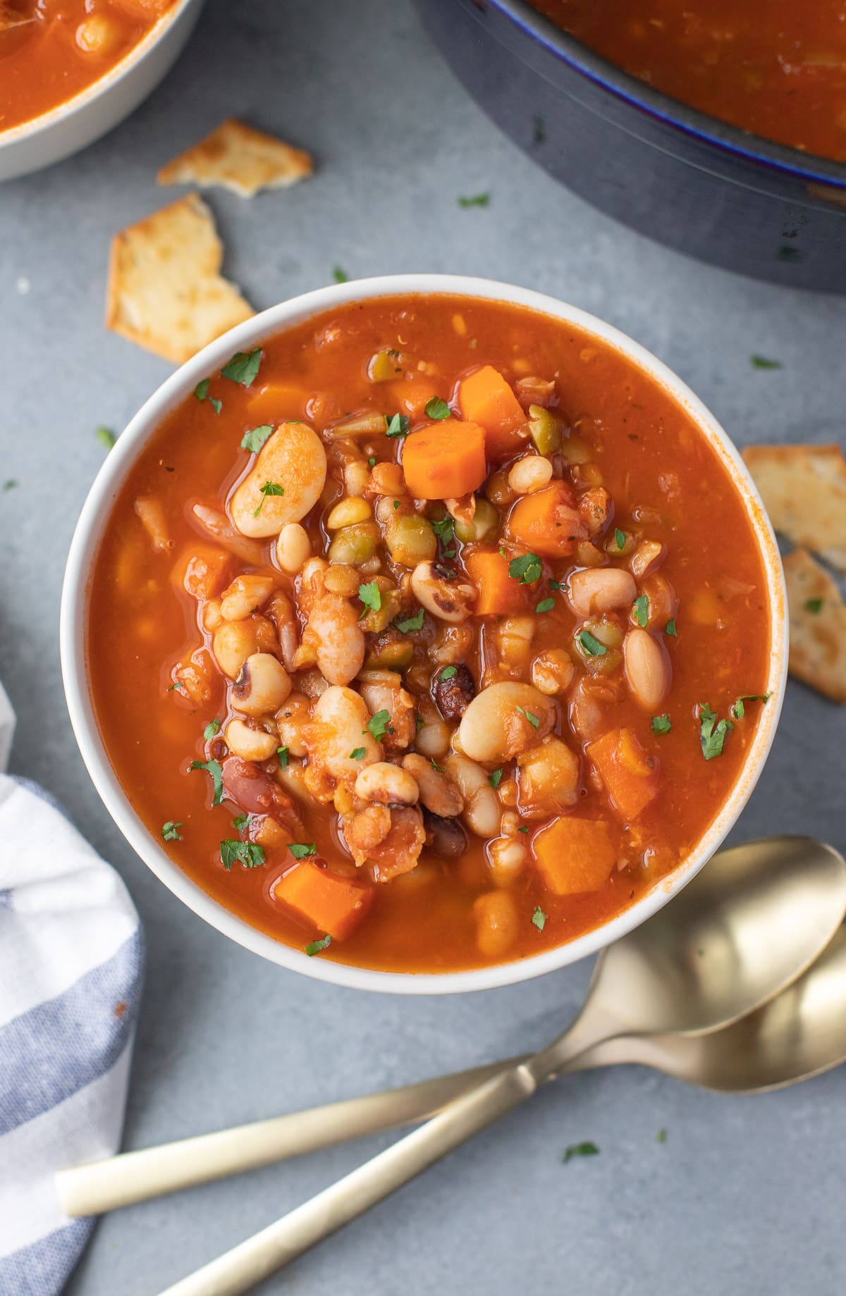 a bowl of 15 bean soup with spoons on the side on a grey background