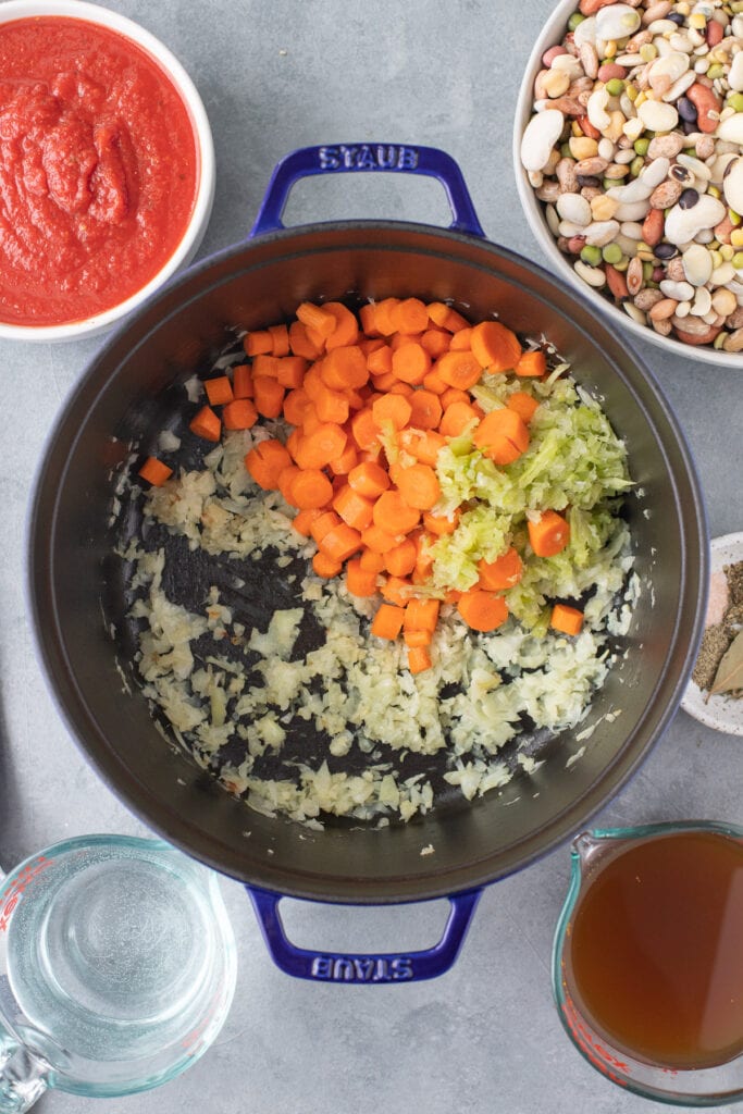Sautéd onion and garlic with celery and carrots added to make 15 bean soup in a dutch oven with the dry bean mix on the side