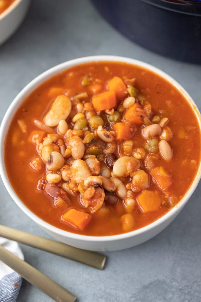 a white bowl full of easy bean soup on a grey background
