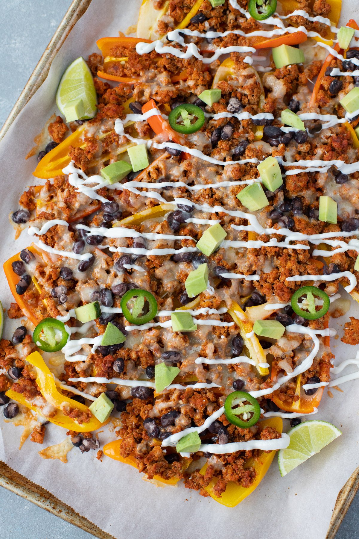 A sheet pan with loaded bell pepper nachos on a grey background