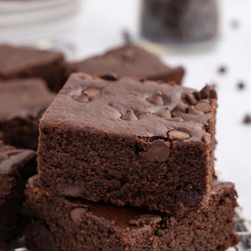 A stack of 2 black bean brownies on a cooling rack with more healthy brownies in the background