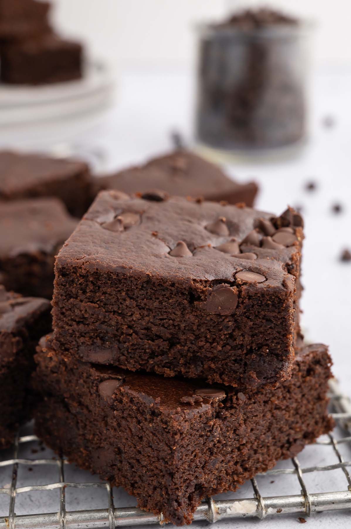 A stack of 2 black bean brownies on a cooling rack with more healthy brownies in the background