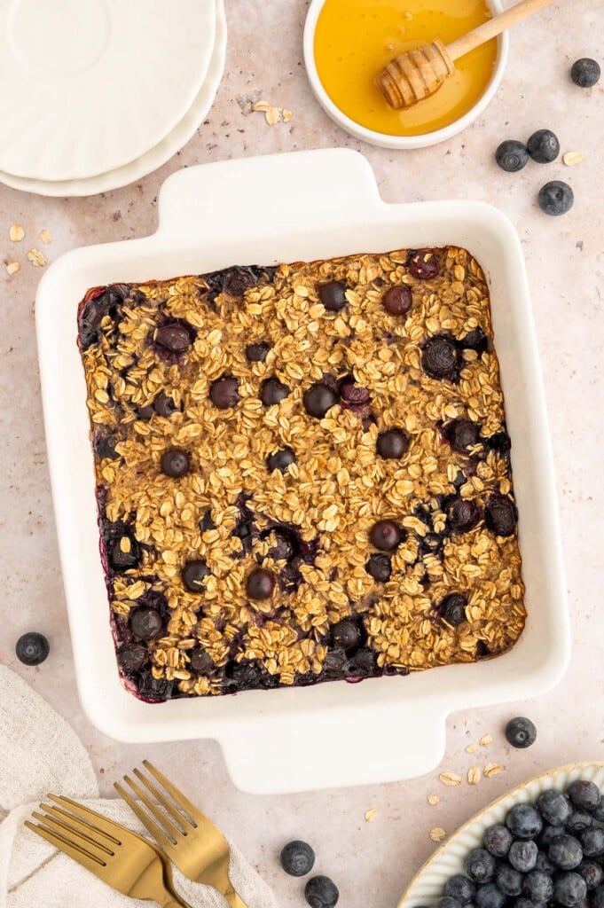 A white baking dish of Healthy Blueberry Baked Oatmeal with blueberries on the side.