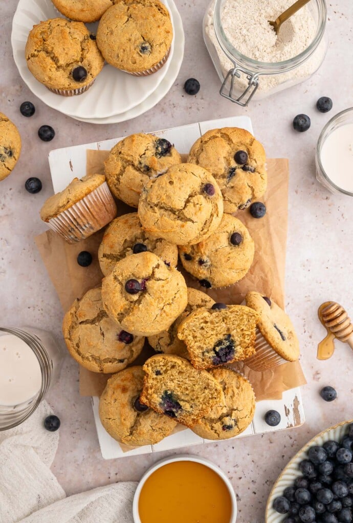 An overhead shot of blueberry protein muffins on a piece of parchment paper with blueberries on the side.