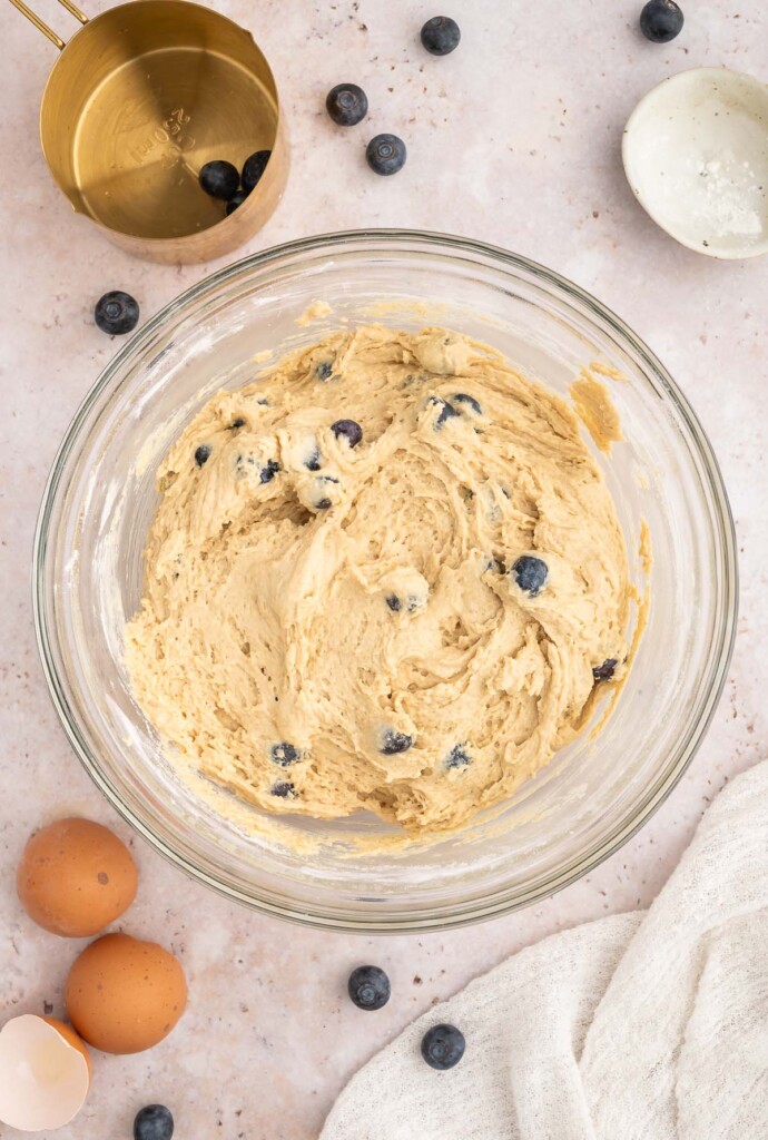 Blueberry Protein Muffin batter in a clear bowl with blueberries on the side. 
