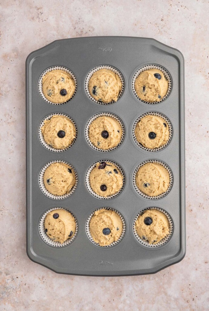 Unbaked blueberry protein muffins in a muffin tin.
