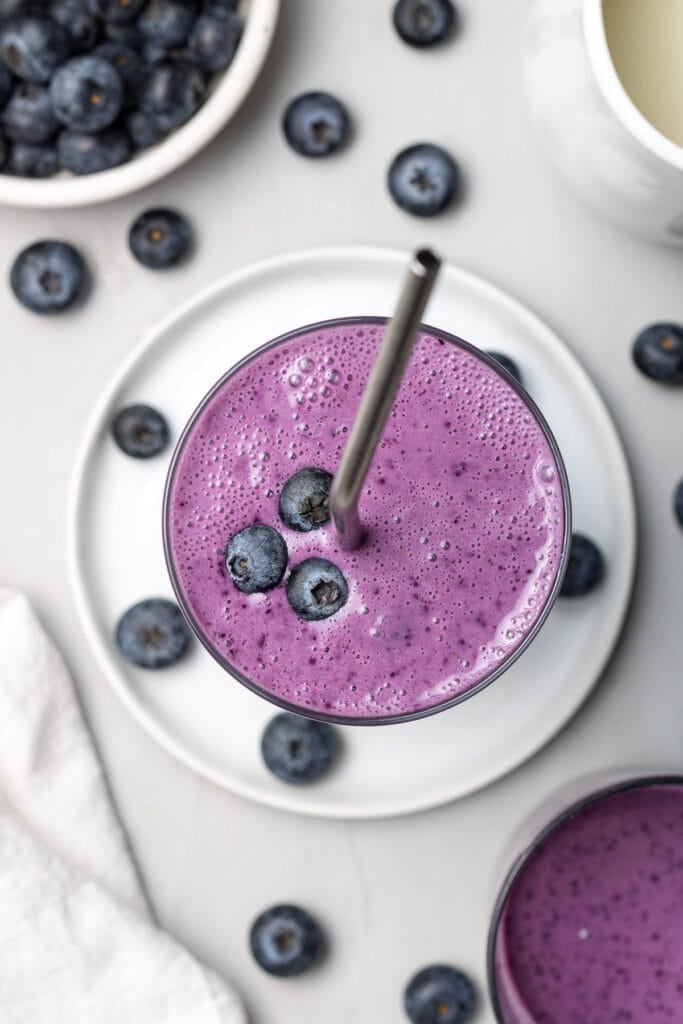 An overhead image of an easy blueberry smoothie recipe on a grey background with berries off to the side