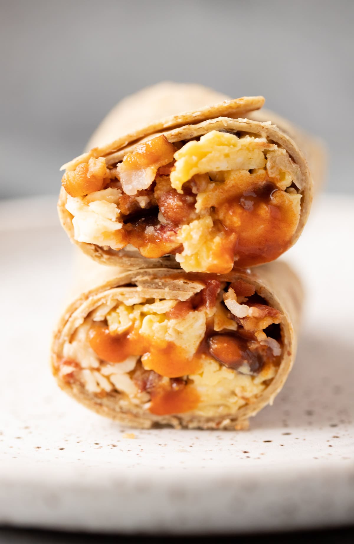 A close up of the best healthy breakfast burritos cut in half and stacked on top of one another.