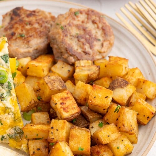 Breakfast Potatoes on a plate with egg white frittata and sausage on the side.