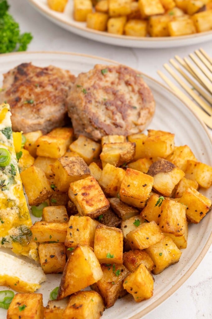 Breakfast Potatoes on a plate with egg white frittata and sausage on the side.