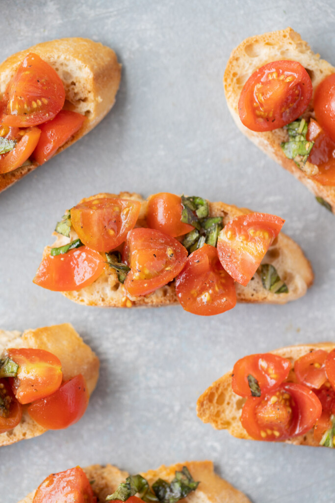 Homemade bruschetta on small baguette toasts on a grey background
