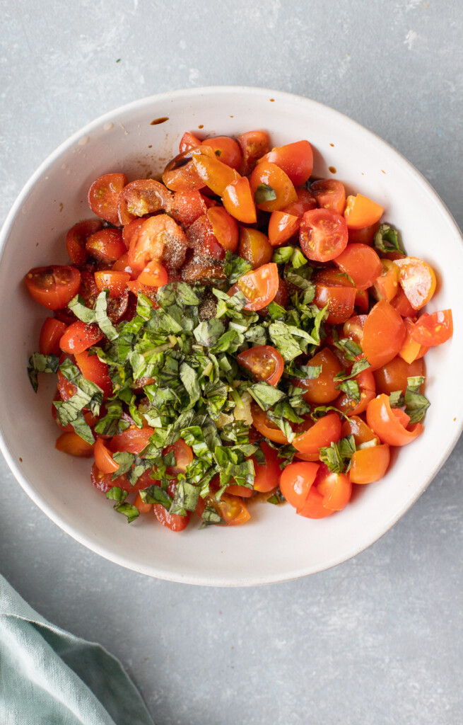 A white bowl of homemade bruschetta before being mixed together