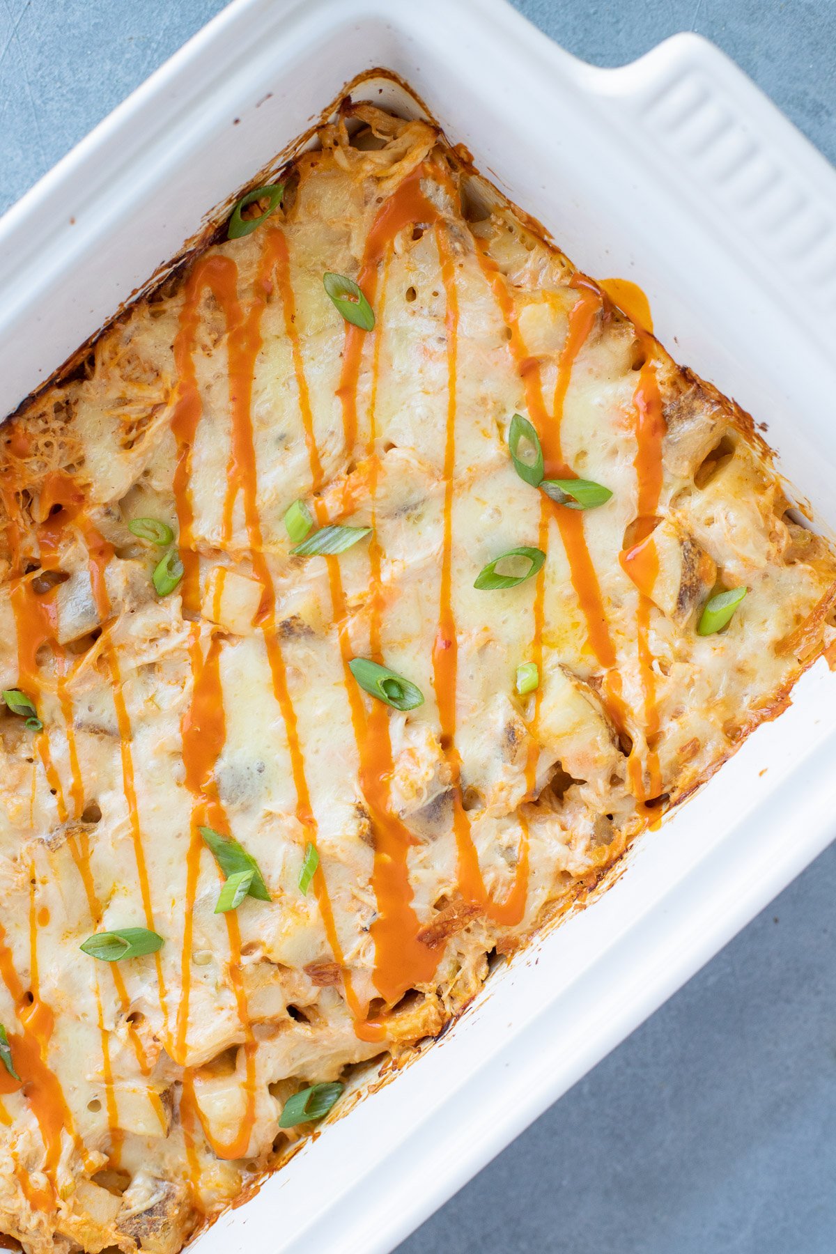 An overhead image of Buffalo Chicken Casserole in a white dish on a grey background