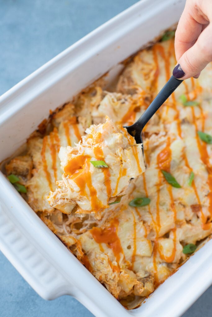 A black spoon taking a scoop out of buffalo chicken casserole