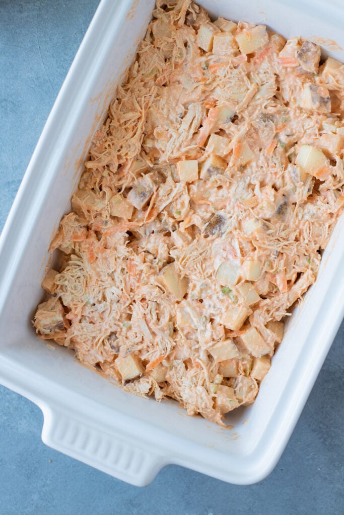 Buffalo chicken casserole in a white casserole dish mixed together before being baked