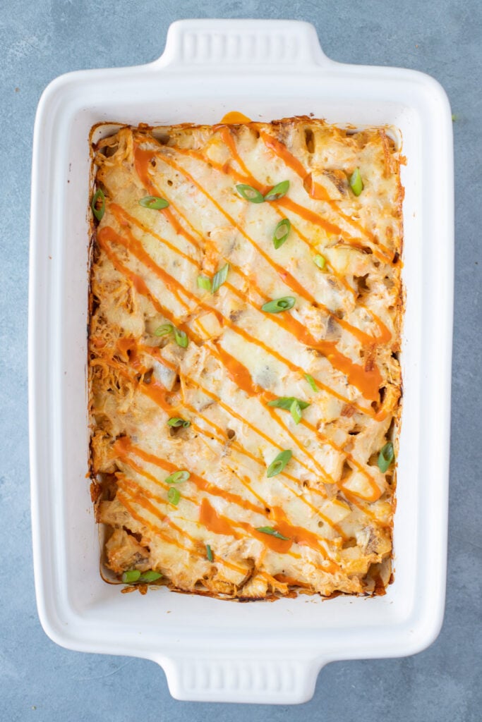 A close up of buffalo chicken casserole in a white casserole dish on a grey background