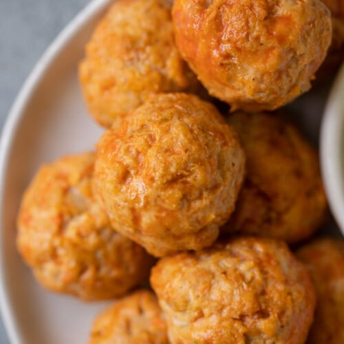 Buffalo Chicken Meatballs stacked on a white plate with a grey background