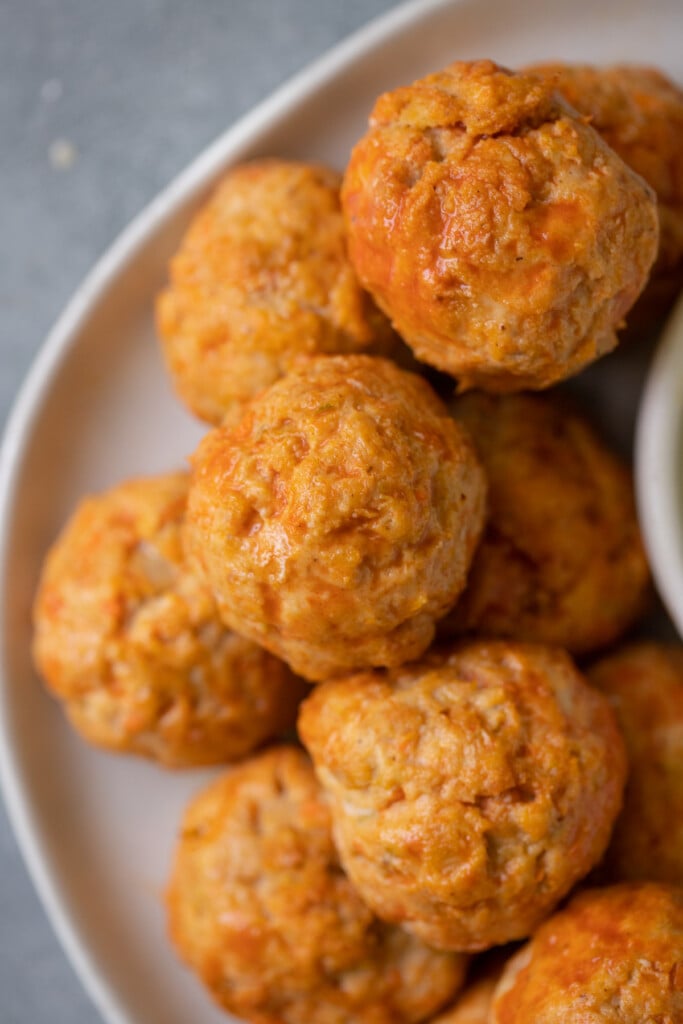 Buffalo Chicken Meatballs stacked on a white plate with a grey background