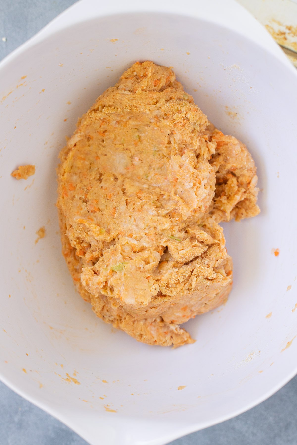 A white bowl with ingredients for buffalo chicken meatballs after being mixed