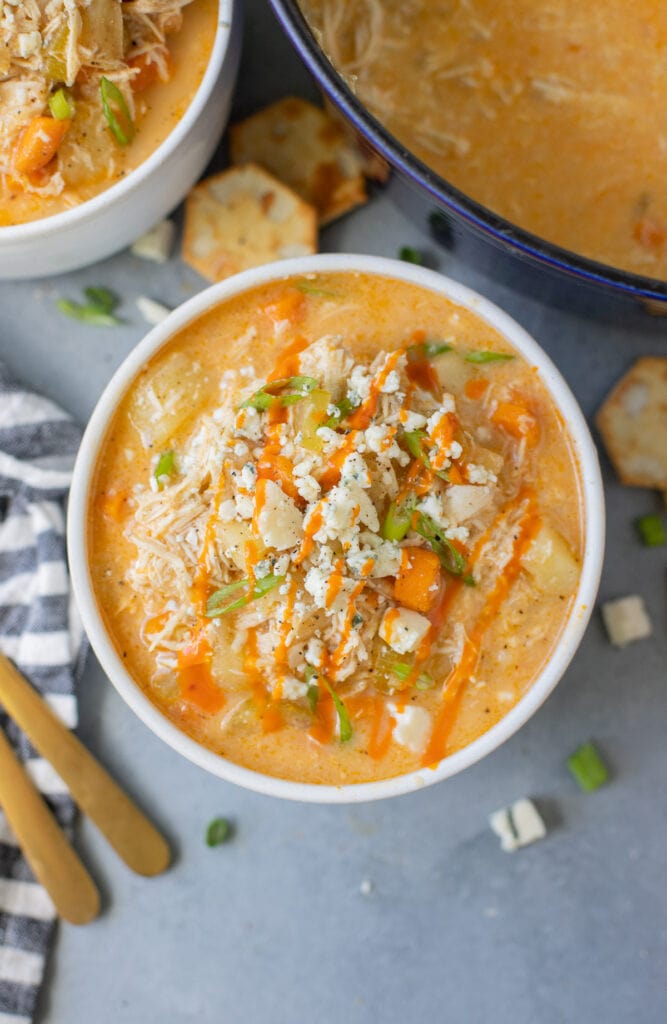 A close up of Buffalo Chicken Soup in a white bowl on a grey background