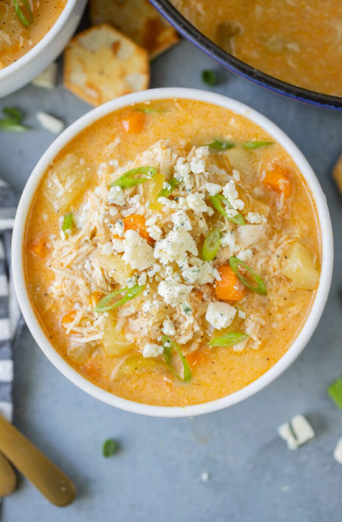 A close up of Buffalo Chicken Soup in a white bowl on a grey background