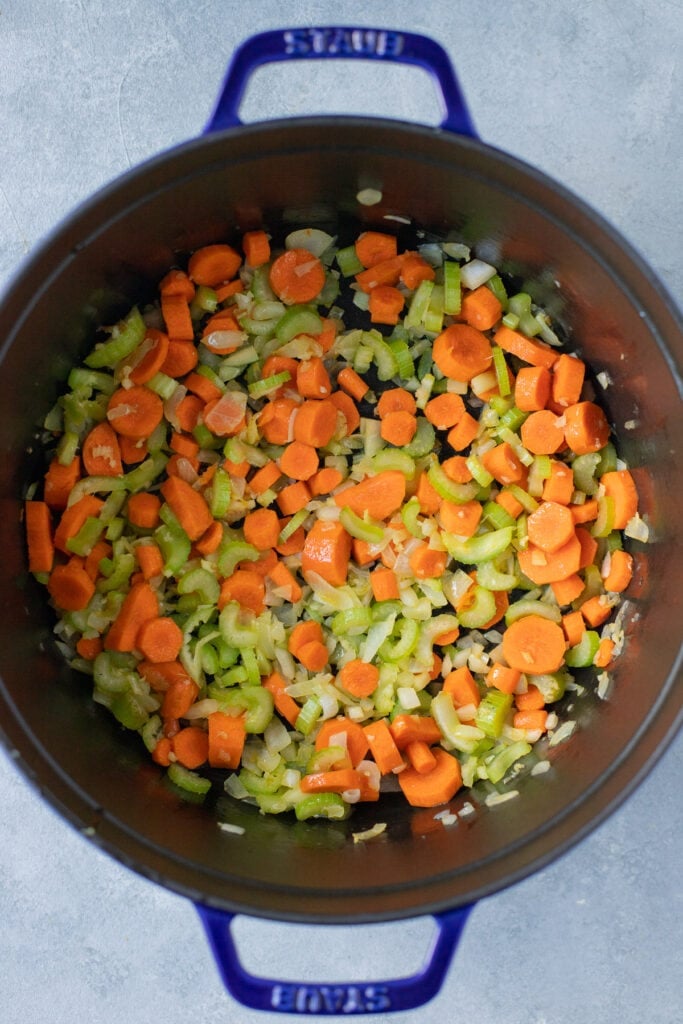 Celery, carrot, onion and garlic cooking in a stockpot in olive oil to make buffalo chicken soup