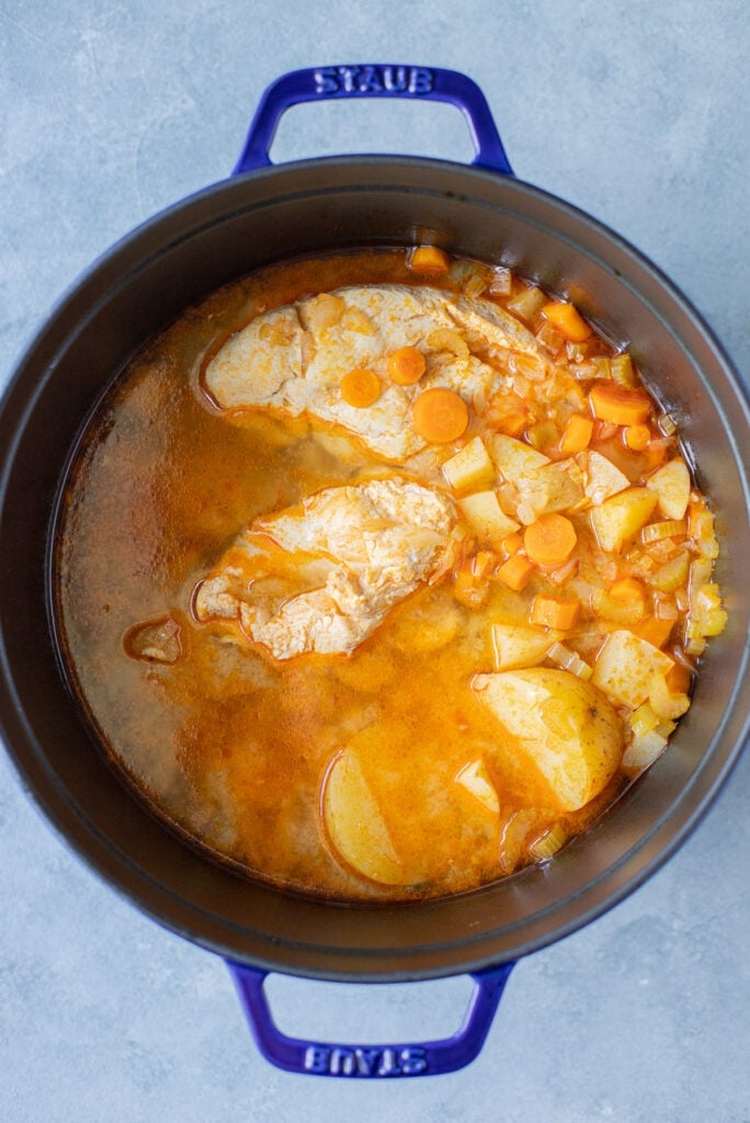 Pot with cooked chicken, potatoes, broth, buffalo sauce, carrots, celery, onion and garlic to make buffalo chicken soup
