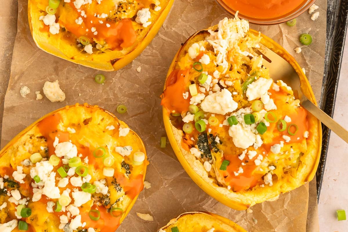 A close up of Easy Buffalo Chicken Spaghetti Squash Boats on a parchment lined baking sheet.