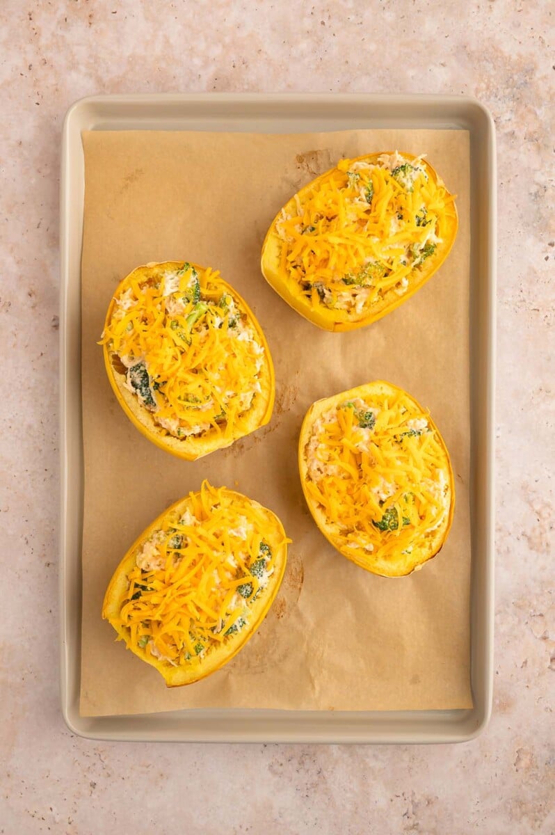 Four buffalo chicken spaghetti squash boats on a parchment lined baking sheet. 