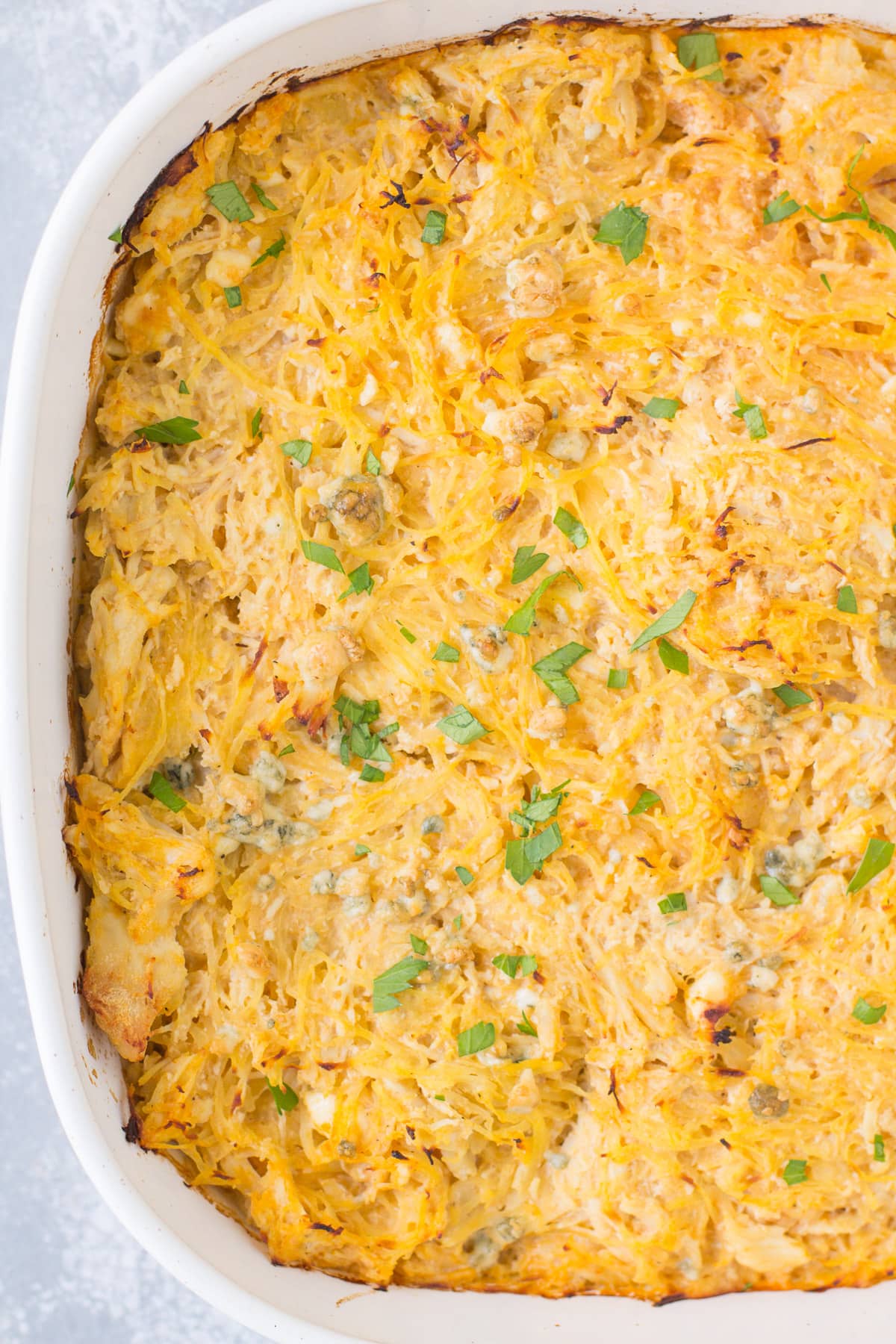 Buffalo Chicken Spaghetti Squash Casserole in a white dish on a grey background.