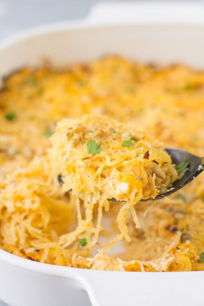 A black serving spoon taking a scoop out of buffalo chicken spaghetti squash casserole. 