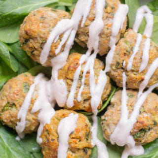 Healthy Buffalo turkey meatballs over a bed of spinach with a greek yogurt drizzle