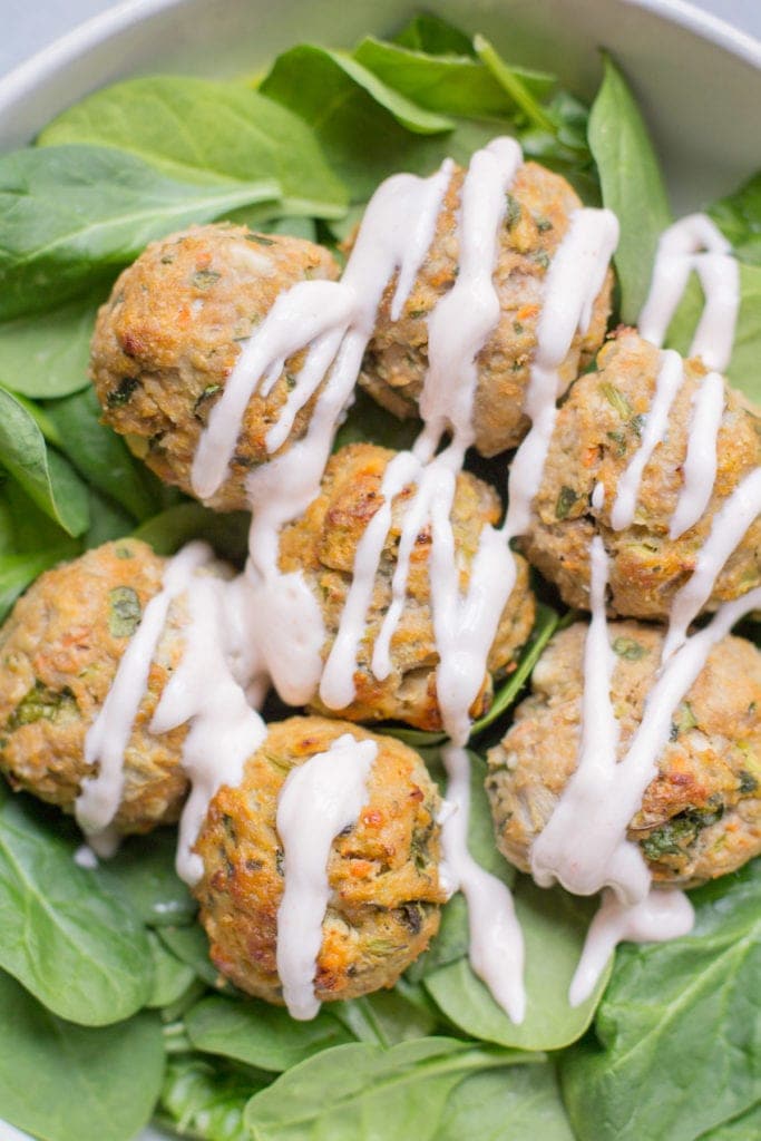 Healthy Buffalo turkey meatballs over a bed of spinach with a greek yogurt drizzle