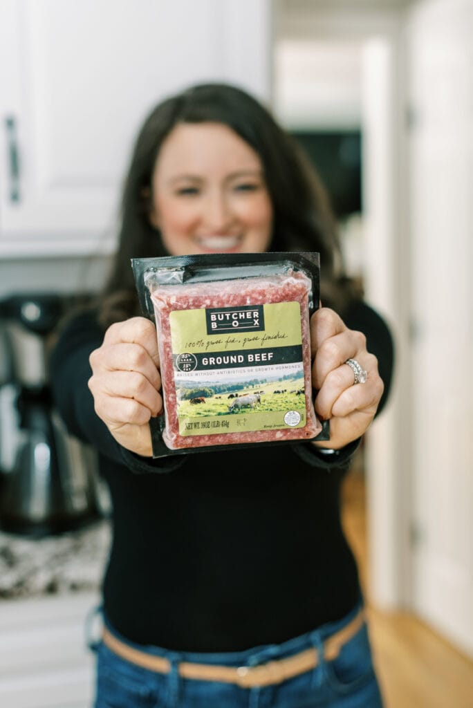 A girl holding up butcher box ground beef - giving an honest butcher box review