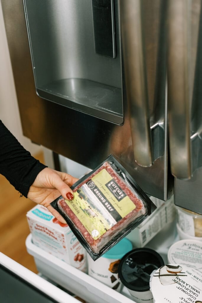A hand putting ButcherBox Ground Beef into the freezer