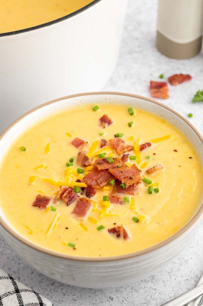 A bowl of cauliflower soup with a dutch oven of soup on the side