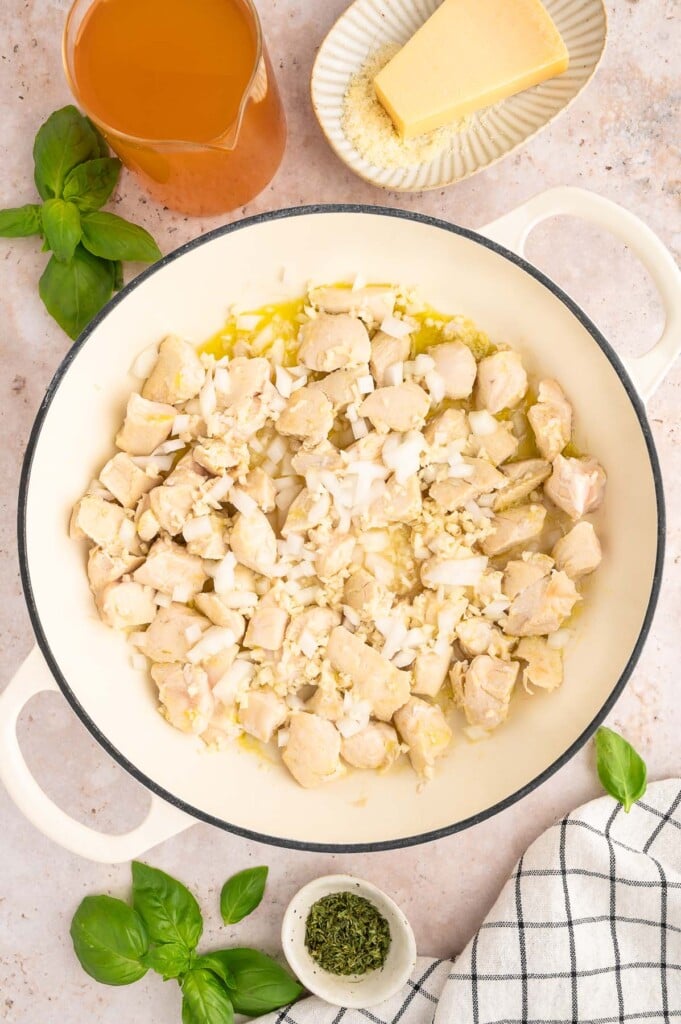 Chicken pieces cooking in olive oil and spices in a dutch oven.